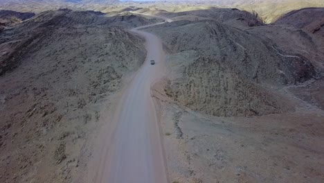 Excelente-Antena-De-Un-Vehículo-De-Safari-En-Jeep-4x4-En-Un-Camino-De-Tierra-A-Través-De-Las-Montañas-Del-Desierto-De-Namib-En-Namibia-África
