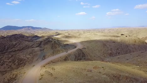Excelente-Antena-De-Un-Vehículo-De-Safari-En-Jeep-4x4-En-Un-Camino-De-Tierra-A-Través-De-Las-Montañas-Del-Desierto-De-Namib-En-Namibia-África-1