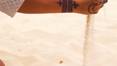 Eine-Schöne-Frau-Mit-Henna-Tattoos-Nimmt-In-Zeitlupe-Sand-In-Der-Hand-Auf