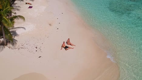 Aerial-Over-A-Couple-Sunbathing-On-A-Perfect-White-Sand-Beach-In-Panama