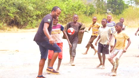 African-Kids-Play-Soccer-Football-On-A-Dirt-Field-With-Brothers-And-Fathers-In-Slow-Motion