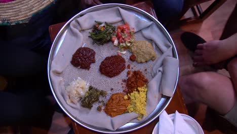 Zeitlupe-Der-Handöffnungskorb-Mit-Traditionellem-äthiopisch-afrikanischem-Injera-Essen-Auf-Einem-Silbernen-Tablett
