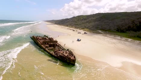 People-approach-an-old-shipwreck-on-a-beach-of-Fraser-Island-off-the-coast-of-Queensland-Australia