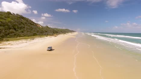 Un-Coche-Conduce-A-Lo-Largo-De-La-Playa-En-Fraser-Island-Frente-A-La-Costa-De-Queensland,-Australia