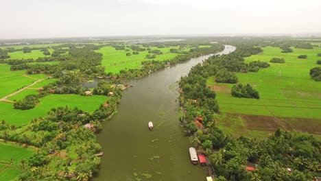 An-aerial-view-shows-a-houseboat-sailing-down-a-river-in-Kerala-India