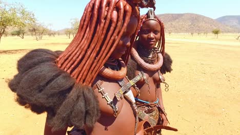 Zwei-Junge-Himba-Stammesfrauen-Zeigen-Ihre-Schlammhaarverlängerungen-Und-Ungewöhnlichen-Geflochtenen-Dreadlock-Frisuren