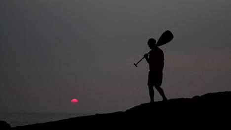 Native-Hawaiian-walks-in-silhouette-holding-a-paddle