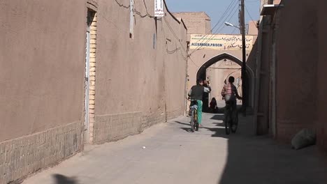 Two-children-ride-bicycles-down-an-ancient-alley-way-in-Iran-