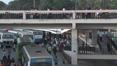 People-gather-in-a-bus-station-getting-on-and-off-buses-and-crossing-an-overhead-walkway