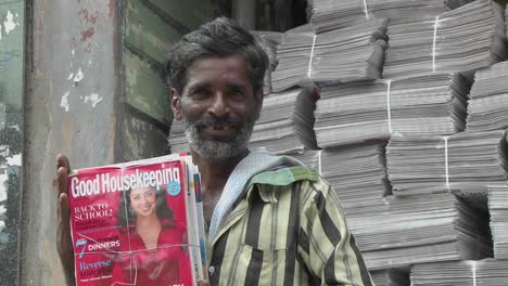 A-man-is-smiling-while-holding-a-bundle-of-magazines