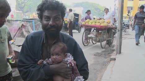Leute-Auf-Einer-Indischen-Straße-Sehen-Etwas-über-Ihren-Köpfen,-Dann-Steht-Ein-Mann-Mit-Einem-Baby-Lächeln-Auf-Und-Geht