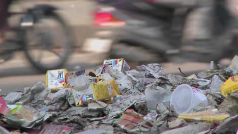 Close-view-of-a-pile-of-trash-set-on-the-side-of-a-busy-street