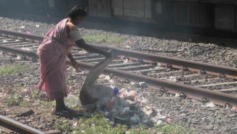 A-woman-dumps-a-bag-of-trash-on-the-railroad-tracks