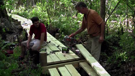 A-father-and-son-work-on-a-wooden-walkway-through-the-Everglades