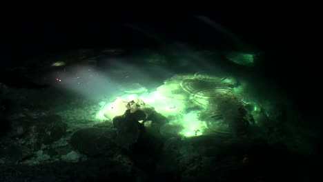 Green-pools-glimmer-in-the-sunlight-at-the-bottom-of-a-cave