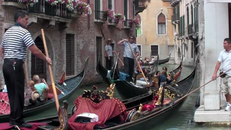 Gondolas-take-people-through-a-narrow-canal-with-buildings-on-each-side-in-Venice-Italy