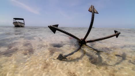 Close-up-of-anchor-at-low-tide-with-boat