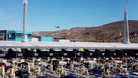 Aerial-Over-The-San-Ysidro-Tijuana-Us-Mexico-Border-Crossing-With-Cars-Lined-Up-For-Miles-And-Border-Patrol-Helicopters-Landing-Distance
