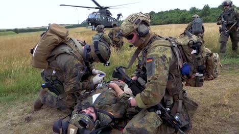 German-Soldiers-Participate-In-A-Rescue-Operation-In-A-Field-With-A-Military-Helicopter-Landing-In-The-Background-2
