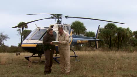 A-Wildlife-Refuge-Law-Enforcement-Officer-Talks-To-A-Helicopter-Pilot-And-Watches-His-Aircraft-Take-Off