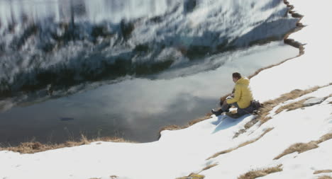 Hiker-Sitting-by-Frozen-Lake