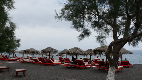 Grecia-Santorini-Perissa-Turistas-Relajándose-En-La-Playa-De-Arena-Negra