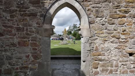 Ireland-Clonmacnoise-A-High-Cross-And-Tourists-Through-A-Window