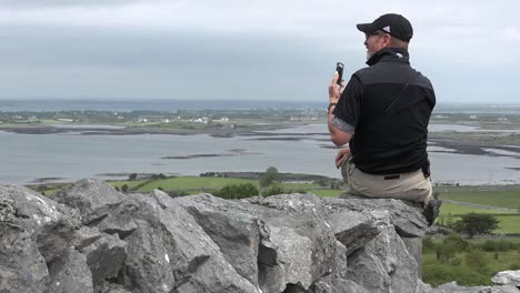 Ireland-Man-On-Stone-Wall-Photographs-With-Phone-Pan