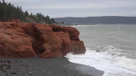 Canada-Bay-Of-Fundy-Waves-Splash-On-Red-Rocks-And-Pebble-Beach