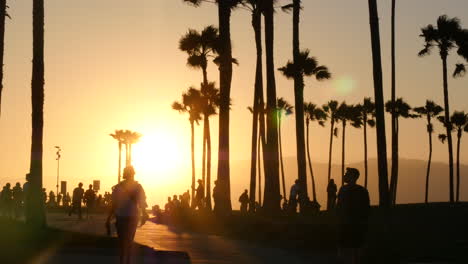 Los-Angeles-Venice-Beach-Park-Sonnenuntergang-Hinter-Beleuchteten-Fußgängern-Und-Palmen