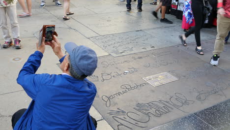 Los-Angeles-A-Tourist-Takes-A-Picture-By-Names-In-Concrete-On-The-Hollywood-Walk-Of-Fame
