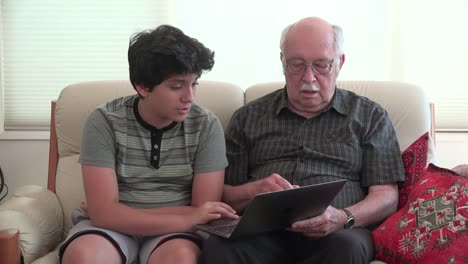 Boy-And-Grandfather-On-Sofa-With-Computer