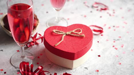Bottle-of-rose-champagne--glasses-with-fresh-strawberries-and-heart-shaped-gift