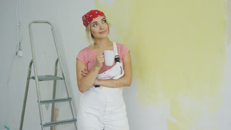 Smiling-woman-painter-standing-with-drink
