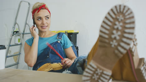 Woman-carpenter-at-workbench-talking-on-smartphone