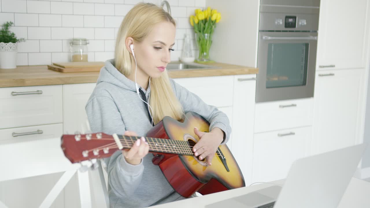 Premium stock video - Girl practicing guitar and using laptop