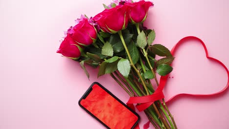 Pink-roses-bouquet-with-hart-shaped-bow-and-mobile-phone-with-copy-space-screen