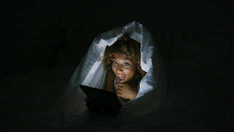 Excited-woman-under-blanket-with-tablet