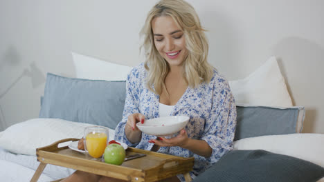 Smiling-woman-having-breakfast-in-bed-