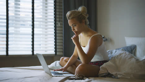 Woman-using-laptop-on-bed-and-thinking