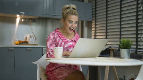 Aufgeregte-Frau-Mit-Laptop-In-Der-Küche