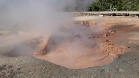 Yellowstone-boiling-red-muddy-water-with-tourist-Lower-Geyser-Basin