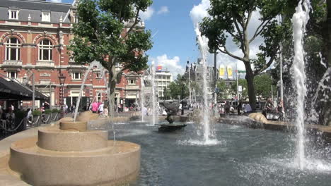 Países-Bajos-Amsterdam-Fuente-Surtidores-Y-Gran-Edificio-De-Ladrillo