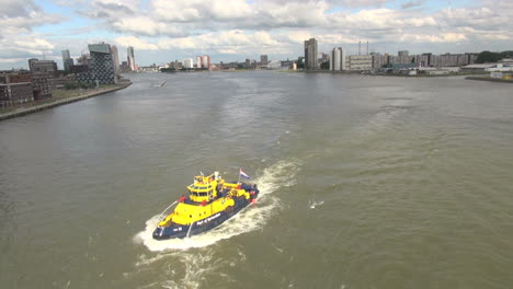 Netherlands-Rotterdam-bright-yellow-boat-in-murky-urban-river