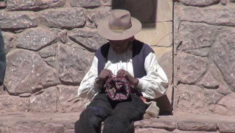 Peru-Taquile-man-weaves-by-hand-in-front-of-stone-wall-18