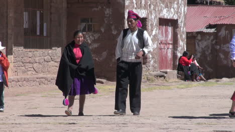 Peru-Taquile-tourists-pass-man-and-woman-in-traditional-clothing-20