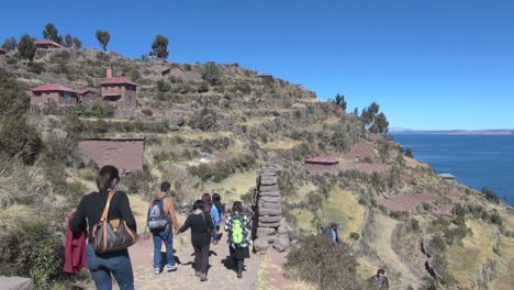 Peru-Taquile-hillside-tourists-walk-through-arch-side-view-27