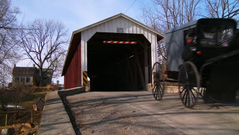 Ein-Amischer-Pferdewagen-Fährt-Durch-Eine-überdachte-Brücke-Entlang-Einer-Straße-Im-Ländlichen-Pennsylvania-2