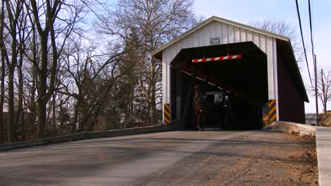 Ein-Amish-Pferdewagen-Fährt-Durch-Eine-überdachte-Brücke-Entlang-Einer-Straße-Im-Ländlichen-Pennsylvania-3