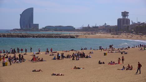 Wide-shot-of-sunbathers-along-the-beach-in-Barcelona-Spain